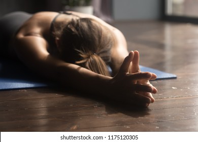 Young sporty attractive woman practicing yoga, doing breathing exercise, relaxation pose, working out, wearing sportswear, indoor close up, yoga studio