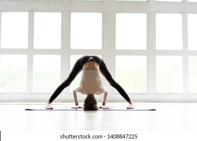 Young sporty attractive woman practicing yoga, doing One Sided Fold exercise, Parsvottanasana, Pyramid pose, working out, wearing sportswear - Powered by Shutterstock