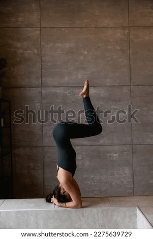 Young sporty attractive woman practicing yoga, doing headstand exercise