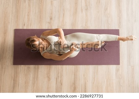 Young sporty attractive women doing pilates toning exercises for abs, crunches to strengthen abdomen using pilates, and wearing sportswear in a yoga studio