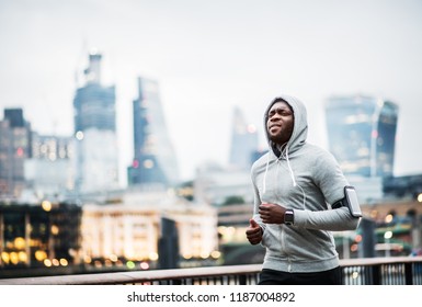 Young Sporty Black Man Runner Running On The Bridge Outside In A City.