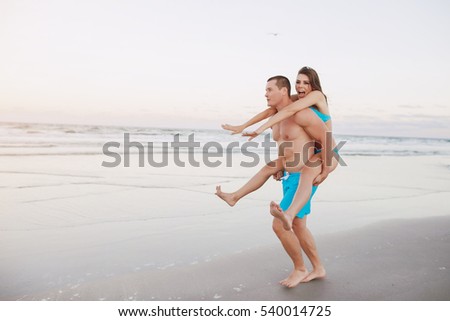 young sporty couple walking on the beach and posing for the photographer