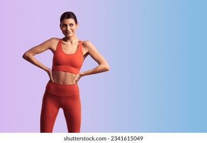Young sporty female wearing red tight sportswear standing with hands on waist against gradient background and looking away - Shutterstock ID 2341615049