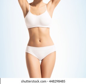 Young, sporty, fit and beautiful girl in sporty underwear over gradient blue background.