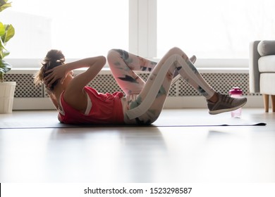 Young Sporty Fit Woman Lying On Mat Floor Doing Bicycle Crunch Fitness Exercise At Home Gym, Healthy Active Teen Girl Training Abs Workout Crisscross Cross Twist Abdominal Sit Ups Alone Indoors