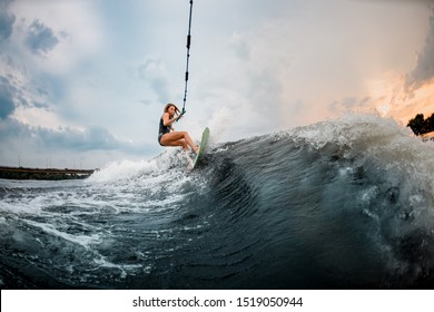 Young sporty girl rides on a green and orange wakeboard in the river near forest - Powered by Shutterstock