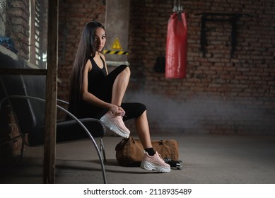 A young sporty girl is tying shoelaces on a sneaker at the gym. - Powered by Shutterstock