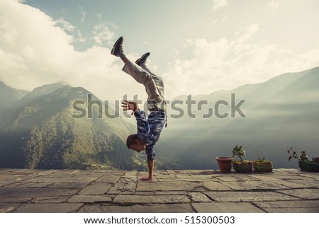 Young sporty man doing handstand exercise in beautiful mountain landscape. Sports outdoor lifestyle