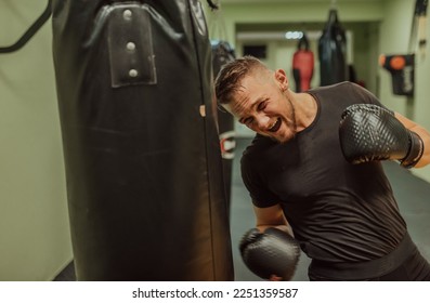 A young sporty man exercise intensively while punching boxing bag in a gym. - Powered by Shutterstock