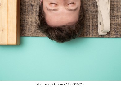 Young Sporty Man Lying In Dead Body Exercise Or Corpse Pose With His Eyes Closed, Savasana Pose Resting After Practice. Top View