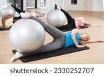 Young sporty men and women doing pilates exercises with fitness ball at gym