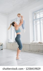 Young sporty mother and baby girl do exercises together in the gym. Parent and child healthy development, fitness and relaxation. Healthy lifestyle concept photo. Toning.