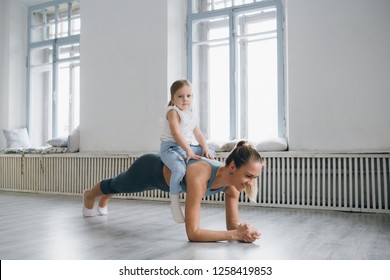 Young sporty mother and baby girl do exercises together in the gym. Parent and child healthy development, fitness and relaxation. Healthy lifestyle concept photo. Toning.