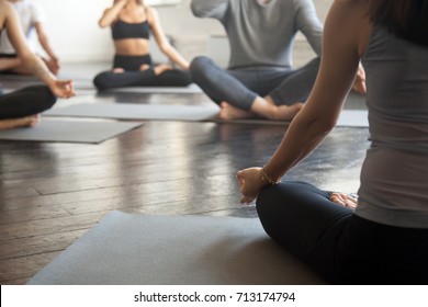 Young sporty people practicing yoga lesson with instructor, sitting, making Alternate Nostril Breathing, nadi shodhana pranayama exercise, working out, close up image. Wellbeing and wellness concept 