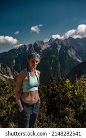Young sporty and tanned woman is posing during a beautiful sunny afternoon hike in slovenian Julian Alps. She is wearing blue clothes and braided hair.