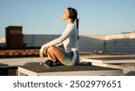 Young sporty woman with big headphones practicing lotus asana. Woman do meditation yoga practice with eyes closed alone. Well being, wellness concept