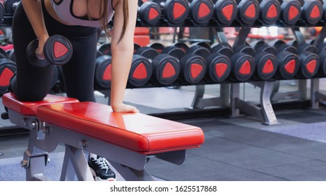 Young sporty woman doing dumbbell row in gym. Sport and exercise concept.