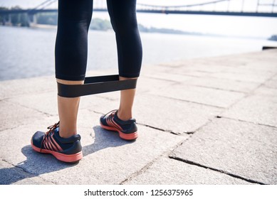Junge sportliche Frau, die Übungen mit Gummiband draußen macht.