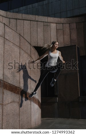 Young sporty woman doing parkour in city. The girl is engaged in freerunning.