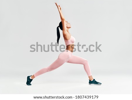 Young sporty woman doing yoga asana Warrior I Pose on white background. Practicing yoga, wellbeing and healthy lifestyle. Virabhadrasana