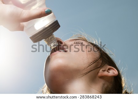 Young sporty woman drinking water from a bottle 
