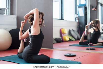 Young sporty woman in gym making stretching