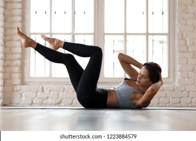 Young sporty woman practicing, doing crisscross exercise, bicycle crunches pose, working out, wearing sportswear, black pants and top, indoor full length, white sport studio - Shutterstock ID 1223884579