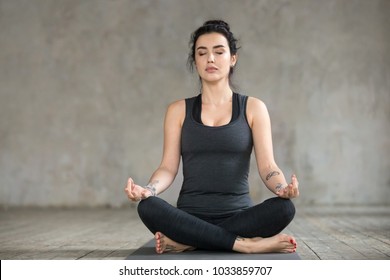 Young Sporty Woman Practicing Yoga, Doing Sukhasana Exercise, Easy Seat Pose, Working Out, Wearing Sportswear, Black Pants And Top, Indoor Full Length, Yoga Studio