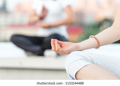 Young sporty woman practicing yoga at class, doing stretching exercise. Close-up detail view of leg and hand