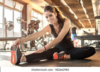 Young sporty woman stretching at gym.