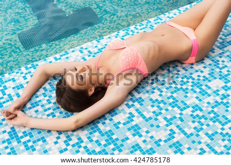 Young and sporty woman in swimsuit. Girl relaxing in a pool at summer. 