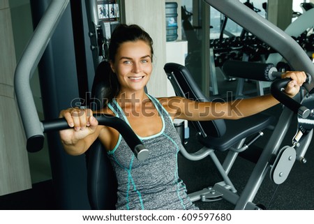 Young and sporty woman using press machine in the gym