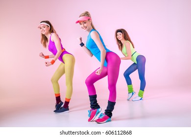 young sporty women doing aerobic exercises isolated on pink