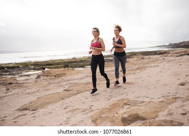 Young Sporty Women Getting Fit Together By Running On The Sand By The Ocean