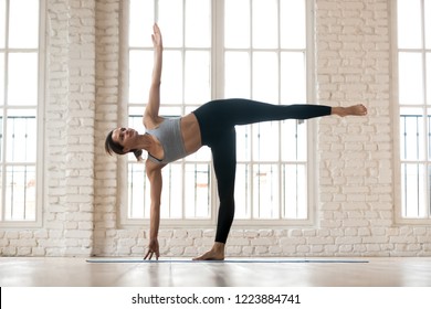 Young sporty yogi woman practicing yoga, doing Half Moon exercise, Ardha Chandrasana pose, working out, wearing sportswear, pants and top, indoor full length, white yoga studio - Powered by Shutterstock