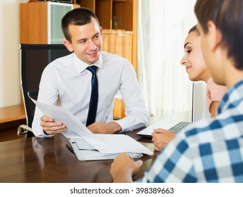 Young spouses and positive salesman with documents at agency