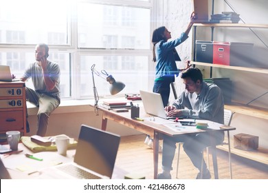 Young Startup Group Working In Modern Office. Open Space, Laptops And Paperwork. Film Effect, Blurry Background, Lens Flare Effect