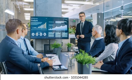 Young Stock Trader Shows to the Executive Managers Cryptocurrency and Trade Market Correlation Pointing at the Wall TV.