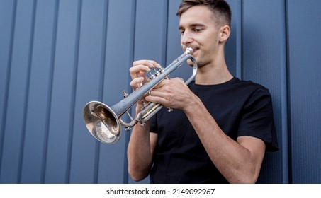 Young Street Musician Playing The Trumpet Near The Big Blue Wall