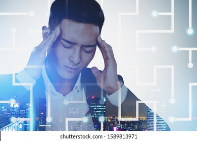 Young Stressed Asian Businessman Standing In Night City With Double Exposure Of Digital Maze. Concept Of Being Tired Of Technology And Overwork. Toned Image