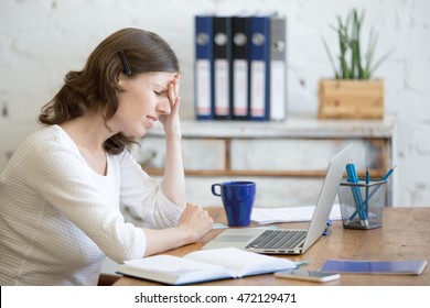Молодая стрессовая бизнесвумен, сидящая перед ноутбуком и трогающая голову с больным выражением. Деловой человек чувствует боль, страдает от мигрени после работы на ПК, перегружен или подавлен