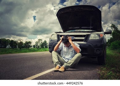 young stressed man having trouble with his broken car looking in frustration on failed engine
