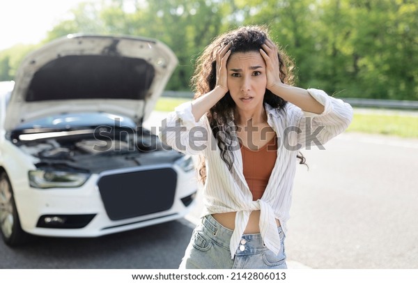 Young stressed woman\
standing on highway near broken car, grabbing her head in terror,\
waiting for breakdown road service. Millennial lady having auto\
accident during travels