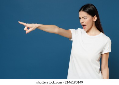 Young strict indignant angry latin woman 20s wearing white casual basic t-shirt point index forefinger finger aside scream shout commanding do it isolated on dark blue color background studio portrait