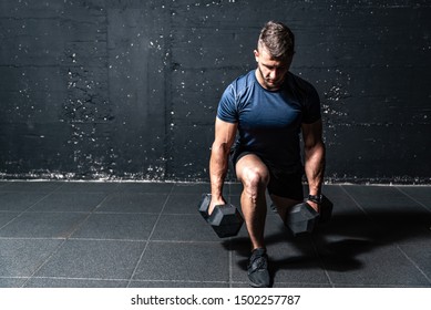 Young strong fit muscular sweaty man with big muscles strength cross workout one leg squat training with dumbbells weights in the gym dark image with shadows real people - Powered by Shutterstock