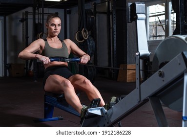 Young Strong Fit Sweaty Powerful Attractive Muscular Woman With Big Muscles Doing Hard Core Row Heavy Cross Training Workout On Indoor Rower At The Gym Real People Rowing Exercise