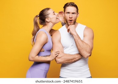 Young strong fitness trainer instructor sporty two man woman wearing blue clothes spend time in home gym whisper gossip and tells secret isolated on plain yellow background. Workout sport fit concept - Powered by Shutterstock