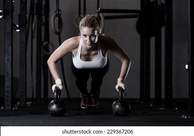 Young strong girl doing push-ups na kettlebells - Powered by Shutterstock