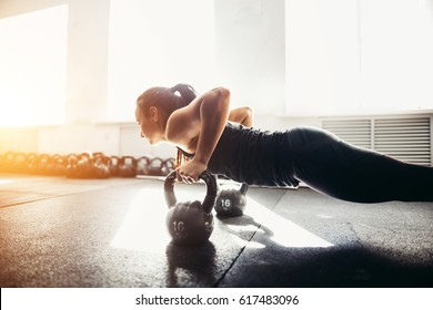 Young strong girl doing push-ups on kettlebells. focus on kettlebells