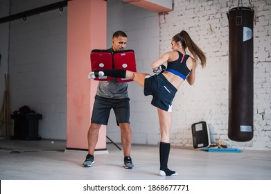 A Young Strong Kickboxer Girl Kicks Her Sparring Partner With A Boxing Paw In A Personal Training Session